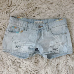 Ljusblåa lågmidjade jeanshorts med slitningar  - Se profil för fler shorts! Så fina! Midja: ca 38 cm rakt över