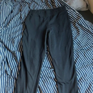 Svarta mjukisbyxor med resårmidja - Svarta mjukisbyxor med elastisk midja och en bakficka. Byxorna är raka i modellen och tillverkade i mjukt bomullstyg, perfekta för chill dagar eller när du vill vara bekväm. Enkla att matcha med hoodies eller t-shirts.