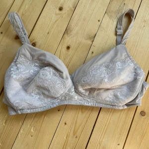 Beige spetsblus från Creem - Supersöt beige blus från Creem med vackra spetsdetaljer över kuporna och justerbara axelband. Blusen har en mjuk och feminin look med transparent spets framtill och släta partier på sidorna. Perfekt för dig som gillar romantiska och stilrena plagg.