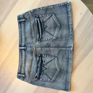 Jeanskjol från Morgan med detaljer - Snygg kort jeanskjol från Morgan med slitna detaljer och snygga fickor. Kjolen har klassisk femficksdesign, bälteshällor och knäppning fram. Perfekt för dig som gillar en avslappnad och trendig stil. Populära så var snabba! Kan gå ner i pris vid snabb affär! 