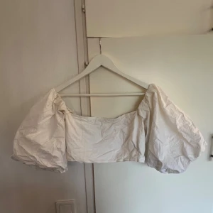 Vit croppad bolerotopp med puffärmar - Superfin vit bolerotopp med stora puffärmar och croppad passform. Toppen är axelbandslös och har en snygg, rak skärning framtill⚡️