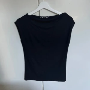 Svart ärmlös topp från 157 - En stilren svart ärmlös topp från 157 med enkel och rak passform. Toppen har bredare axlar och en klassisk rund halsringning. Perfekt att matcha med jeans eller kjol för en clean look.