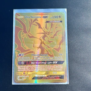 Ultra Necrozma GX - Sällsynt och glittrande Ultra Necrozma GX Pokémonkort! Perfekt för samlare och spelare som vill boosta sin lek med en mäktig Ultra Beast. Kortet har coolt guldholografiskt motiv och är i fint skick – ett måste för alla Pokémonfans!