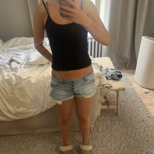 Ljusblå jeansshorts Tally Weijl - Snygga ljusblå lågmidjade jeansshorts från Tally Weijl med slitna detaljer och uppvikta benslut. Modellen är lågmidjad med flera knappar framtill och klassiska fickor både fram och bak. Perfekta för varma dagar och en chill look.