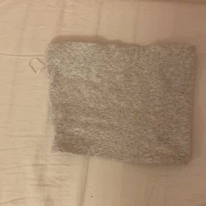 Grå ribbad tubtopp från Zara - Säljer en ljusgrå ribbad tubtopp från Zara i storlek M. Enkel och stilren bandeau-modell som är perfekt att matcha med jeans eller kjol. Mjuk och stretchig bomullsblandning som sitter skönt och följer kroppen.