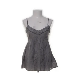 Grå linnetopp från Day Birger et Mikkelsen - Supersöt grå linnetopp med tunna axelband från Day Birger et Mikkelsen. Toppen har v-ringning med snygga silkiga detaljer och ett luftigt, lätt utställt fall. Tillverkad i bomull med silkesdetaljer för en lyxig känsla. Perfekt för varma dagar!