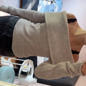 Beige ribbad offshoulder stickad tröja - Superfin beige stickad tröja med ribbad struktur och bred offshoulder-krage. Perfekt för dig som vill ha en mysig men ändå snygg look. Långärmad och sitter skönt på kroppen.