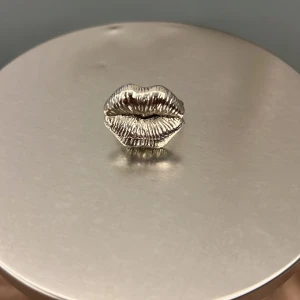 Statementring i silver med läppar - Cool ring i silverfärgad metall med ett stort läppmotiv framtill. Perfekt accessoar för dig som vill sticka ut och addera en edgy touch till din stil. Ringen har en blank finish och detaljerad struktur på läpparna.