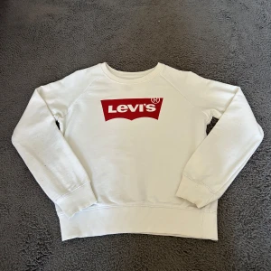 Vit Levi’s sweatshirt - NYPRIS: 499 Vit sweatshirt från Levi's med klassisk röd logga framtill. Tröjan har rund hals, långa ärmar och ribbade muddar vid ärmslut och nederkant. Perfekt för en avslappnad och stilren look. 