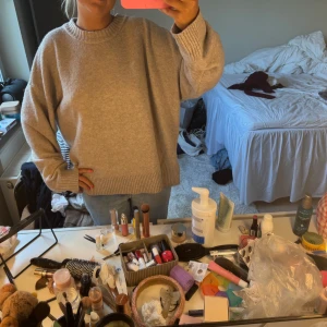 Beige stickad oversized tröja - Supermysig beige stickad tröja med oversized passform och breda ribbade muddar vid ärmslut och halsringning. Perfekt för lager-på-lager och chill dagar. Enkel att matcha med jeans eller kjol för en avslappnad look.