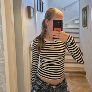Svartvit randig långärmad tröja - Säljer en svartvit randig långärmad tröja med tight passform med lite croppad längd. Tröjan har en lite fläck (se bild 4) längst ner på magen. Går möjligtvis bort vid tvätt. Utöver det fint skick!! Stl xs, från H&M
