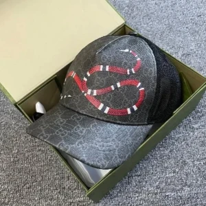 Gucci keps med ormtryck - Snygg keps från Gucci i mörkgrått med klassiskt GG-mönster och en röd, vit och svart orm på framsidan