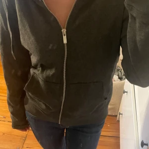 Mörkgrå hoodie från ONLY med dragkedja -  Mörkgrå Zip hoodie från ONLY i storlek M. mjuk insida. vet ej om tröjan är oversized i modellen, eftersom jag inte är storlek M. Jag är storlek XS/S o den sitter lite oversized på mig