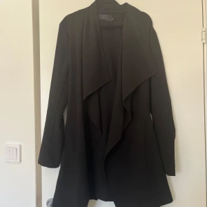 Svart kappa från ONLY med bälte - Tunn svart kappa från ONLY med snyggt fall och knytbart bälte i midjan.