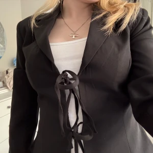 Svart kavaj med knyt från Gina Tricot - Säljer en svart fitted kavaj från Gina Tricot i storlek XS. Den har aldrig kommit till användning och har därav prislapp kvar.