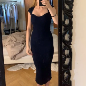 Mörkblå ribbad långklänning - Säljer en mörkblå, tight ribbad långklänning med korta ärmar och snygg v-ringning. Klänningen har en slits bak som gör den extra bekväm och ger en stilren siluett. Perfekt för dig som gillar en enkel men elegant look.