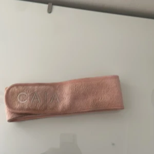 Rosa frotté diadem från CAIA -  Ett smink pannband från CAIA i mjuk frotté med broderad logga framtill. Perfekt för att hålla håret borta vid sminkning eller hudvård. Sitter bekvämt runt huvudet och stängs med kardborre. 