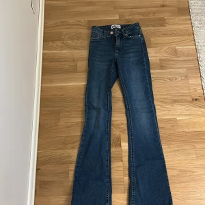 Blå bootcut jeans från ONLY - Snygga blå jeans från ONLY med klassisk bootcut-modell. Jeansen har fem fickor, normal midja och är tillverkade i stretchig denim för en bekväm passform. Perfekta till sneakers eller boots för en cool vardagslook.