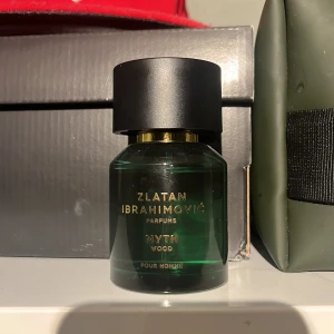 Zlatan Ibrahimović Myth Wood Parfym - En snygg parfym i mörkgrönt glas med svart och guld detaljer från Zlatan Ibrahimović. Doften heter Myth Wood och är en herrparfym. Doftar maskulint med träiga noter. Näst intill oanvänd vilket ni ser på bilden.