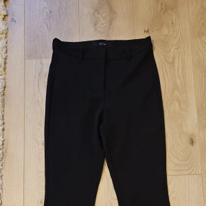 Svarta utsvängda kostymbyxor - Snygga svarta kostymbyxor. Byxorna är utsvängda och har hög midja. Perfekta till en dressad look. Storlek 32. 