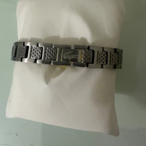 Lacoste armband i silverfärgat stål - Snyggt armband från Lacoste i silverfärgat stål med länkdesign och graverad krokodil på spännet. Armbandet har mönstrade länkar som ger en cool och modern känsla. Perfekt accessoar för dig som gillar stilrena detaljer och ikoniska märken. Kan sänka priset 