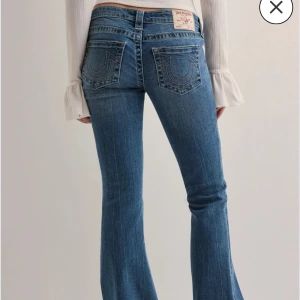 Blå bootcut jeans från True Religion - Snygga blå jeans från True Religion med klassiska kontrastsömmar och ikoniska bakfickor. Modellen har bootcut-ben och låg midja, tillverkade i mjukt denim med lätt tvättad look. Köpta i vintras och inte använda mycket, ser helt nya ut förutom lite slitna längst ned på ena benet. Kan skicka bild! Nypris 1400. 25/32