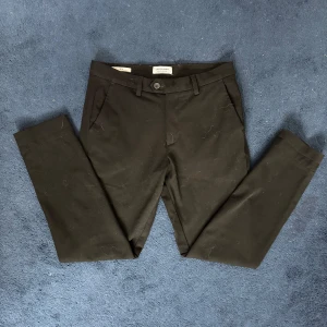 Svarta chinos från Jack & Jones slim M - Svarta chinos från Jack & Jones Pants Studio i slim fit. Byxorna är i storlek 31/30 och sparsamt använda. Sitter bra på mig som är 180cm och 75kg. Tveka inte att skriva vid funderingar 💯