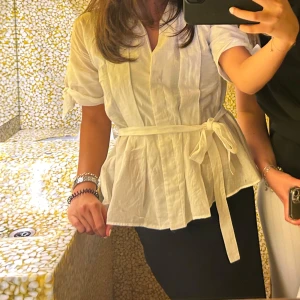 Vit blus från Zara - Superfin vit blus från Zara med knytband i midjan och korta ärmar med knyt-detalj.