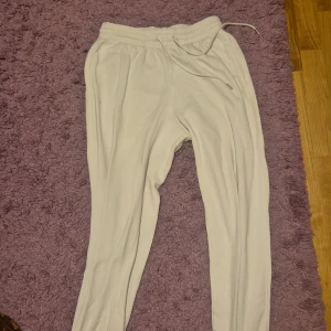Ljusgrå mjukisbyxor med snörning - Säljer ett par ljusgrå mjukisbyxor med elastisk midja och snörning. Byxorna har en avslappnad passform och är perfekta för chill dagar. Tillverkade i mjukt material som känns skönt mot huden.
