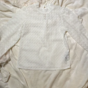 Tröja i spets - En vit tröja i spets med en liten krage från JDY i storlek XS. Ganska genomskinlig.