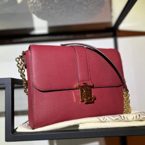 Mörkröd /vinröd axelväska från Ralph Lauren - Säljer en snygg mörkröd axelväska från Lauren Ralph Lauren i präglat skinn. Väskan har guldfärgad kedjerem och RL-logga framtill. Insidan är fodrad med mönstrat tyg och har dragkedjefack för småsaker. Perfekt storlek för det viktigaste och riktigt stilren look. Sparsamt använt, Välvårdad. Köpt från zalando. Ord pris 3999kr