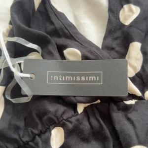 Svart prickig halterneck body Intimissimi - Supersöt svart body från Intimissimi med stora vita prickar och halterneck. Djup v-ringning och resår i midjan ger en snygg passform. Tillverkad i mjuk satin som känns lyxig mot huden. Fick i present så aldrig andvänd. Lappen kvar. S.