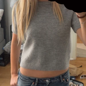 Grå croppad stickad tröja från Zara - Supermjuk grå stickad tröja från Zara med kort ärm och croppad passform. Rund halsringning och ribbade kanter. Knappast andvänd. Super fint skick