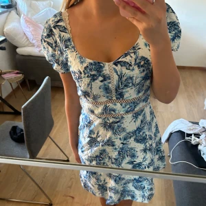 Blåvit blommig kortklänning - Supersöt kortklänning med blått blommönster på vit botten. Klänningen har puffärmar, spetsdetaljer och markerad midja. Perfekt för sommarens alla tillfällen 💕Storlek M men är något liten i storlek så S/M. Orginalpriset var 1549kr men jag säljer denna helt oanvända för 500kr💗