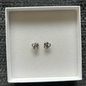 Silverfärgade örhängen med hjärtan - Snygga små örhängen i silverfärg med hjärtformad design och glittriga detaljer.