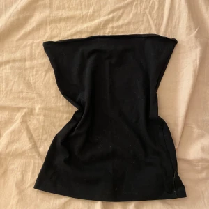 Svart tubtopp  - En klassisk svart tubtopp från H&M i storlek XS. Toppen är axelbandslös och har en enkel, stilren design som sitter tight mot kroppen. Perfekt att styla med jeans eller kjol 