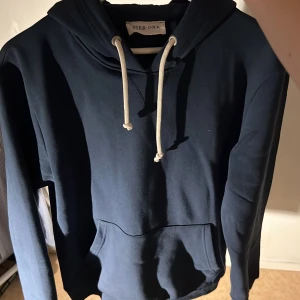 Mörkblå hoodie från Pier One - Pier one hoodie med vita snören. Nästan nyskick, endast testad! Inga defekter eller så. Nypris runt 250kr mitt pris 150kr. 100kr skillnad för att köpa den här som bara blivit testad. Kontakta mig om du har frågor 