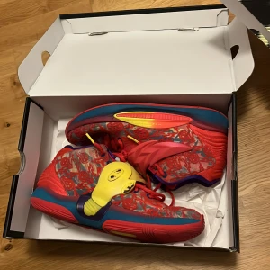 Kd 14 - Unika Nike KD sneakers med färgstark design i rött, blått, gult och lila. Skorna har mönstrad mesh, coola detaljer i plast och snörning. Sulan är röd med blå och gula inslag. Perfekta för dig som vill sticka ut med din stil.