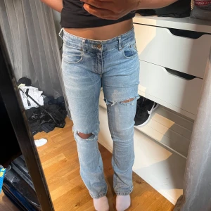 Ljusblå bootcut jeans med slitningar - Säljer ett par ljusblå jeans från Lois med bootcut passform och snygga slitningar vid knäna. Jeansen har klassisk femficksdesign, lågmidja och är gjorda i mjukt denimtyg. Jeansen har ett litet hål i innerbenssömen, men är enkelt att fixa med nål och tråd! 🥰