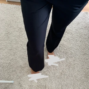 Svarta kostymbyxor med raka ben - Säljer ett par svarta kostymbyxor med raka ben och midwaist passform. Byxorna har hällor för bälte och klassisk stängning fram. Snygga och stilrena, perfekta till en trendig look. PETITE 