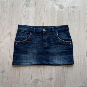 Blå lågmidjad jeanskjol  - Blå jeanskjol från Zero i fint skick. Storlek 38 och passar S/M. Tvärs över midjan är det 39 cm + stretch och den är ca 30 sm lång (längs med sidan). Använd gärna köp nu!
