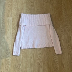 Ljusrosa offshoulder stickad tröja Gina Tricot - Superfin ljusrosa stickad tröja från Gina Tricot med bred ribbad offshoulder-krage. Tröjan har lång ärm och ribbade muddar vid ärmslut och nederkant. Perfekt för dig som gillar en söt och trendig look!