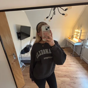 Svart sweatshirt Los Angeles Gina Tricot - Cool svart sweatshirt från Gina Tricot med tryck 'Los Angeles California' i vitt framtill. Oversized fit med breda muddar vid ärmslut och nederkant. Perfekt till jeans eller leggings för en avslappnad vibe.