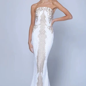 Vit och champagnefärgad långklänning - Säljer en elegant axelbandslös långklänning i vitt med champagnefärgade detaljer och mönster. Klänningen har figurnära passform och vackra broderade partier. Klänningen har endast använts en gång och är därav i nyskick. Nypris: 3179 kr