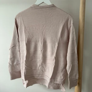 Ljusrosa tröja från River Island - Ljusrosa tröja från River Island med ribbade detaljer upptill, vid ärmslut och nederkant. Långärmad och i mjukt material som känns skönt mot huden. 