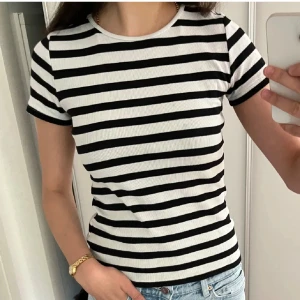 Randig ribbad t-shirt svart/vit - Säljer en superfin randig åtsittande/fitted t-shirt. Den är kortärmad och har en superfin passform, perfekt nu inför hösten. Materialet är mjukt och skönt mot huden. Passar perfekt till jeans eller svarta kostymbyxor under hösten!!💕strl: xs/s