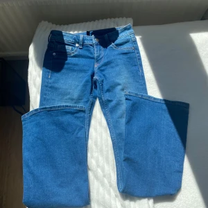 Blå bootcut jeans från Divided - Snygga blå jeans från Divided i klassisk bootcut-modell. Jeansen har fem fickor, bälteshällor och stängs med knapp och dragkedja. Tillverkade i mjukt denimtyg som sitter skönt och ger en tidlös look.