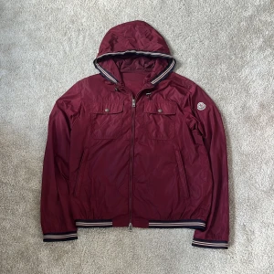 Moncler windbreaker  - Hej! Säljer denna riktigt feta Moncler vindjackan i den sällsynta modellen Jeanclaude! Jackan har en riktigt unik och snygg vinröd färg och är i storlek 3 vilket motsvarar en M! Denna jacka har 3 kontrastfärger i marinblått, vitt och rött vilket representerar märket 😁nypris runt 10000kr. Mitt pris är endast 3000kr! 🙌jackan har 2 pinholes längst nere vid jackan (inget som syns) (bild 4)! Äkta‼️Skriv vid minsta intresse! Mvh DC 🔹