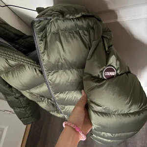Olivgrön pufferjacka från Colmar - Snygg olivgrön pufferjacka från Colmar med klassisk logga på ärmen. Jackan har dragkedja framtill, två fickor och en cool, quiltad look. Perfekt för kalla dagar när du vill vara både varm och stilren. Kan finnas en osynlig fläck någonstans skriv priv för mer information. Kostar 6000kr originellt 