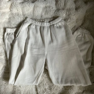 Vita mjukisbyxor med resår - Säljer ett par vita mjukisbyxor från Gina Tricot med resår i midjan och vid bensluten. Byxorna har en avslappnad passform i ett lite tjockare material. Syns att de är använda, men är hela och funkar som de ska.